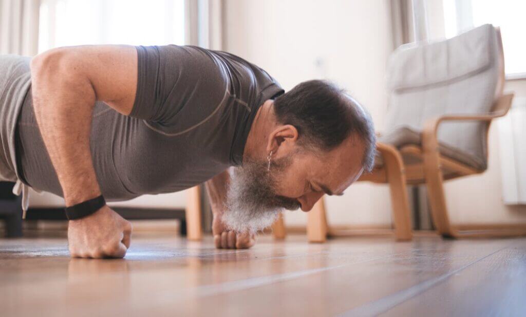 Workout zuhause Mann trainiert Liegestütze am Boden.
